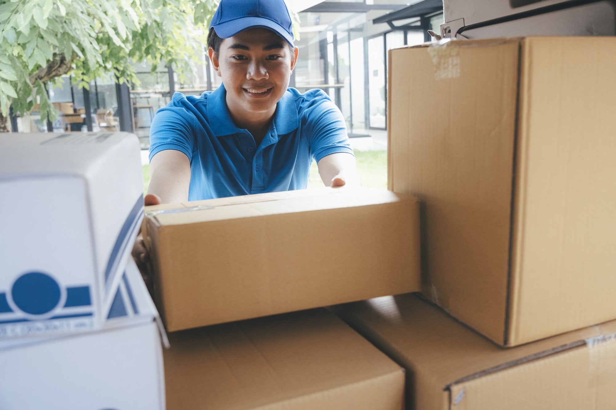 Delivery man loading cardboard boxes in a delivery van